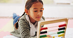 Child, student and play with abacus in home for education, studying and maths homework. Girl, kid and relax with academic toys for learning literacy, calculation solution and numeracy skills on floor