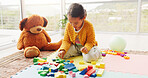 Toys, playing and child on floor with building blocks for learning, development and creative skills. Home, morning and girl with color, shapes and teddy bear for growth, education and puzzle in house