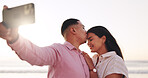 Selfie, kiss and couple at beach with sunrise for travel memory, social media and bonding on weekend. Marriage, love and photo of man and woman by ocean for relationship, picture and post on holiday