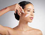 A beautiful mixed race woman using a rose quartz derma roller during a selfcare grooming routine. Young hispanic woman using anti ageing tool against grey copyspace background