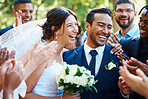 Joyful bride and groom standing together while greeting guests after their wedding ceremony. Newlyweds looking happy while friends and family congratulate them on their marriage