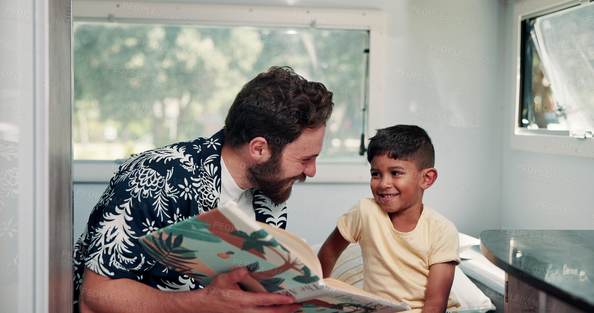 Buy stock photo Father, boy or reading book in caravan for vacation, interracial family or story for knowledge development. Travel, happy man or child with literature for language skills, bonding or learn on holiday