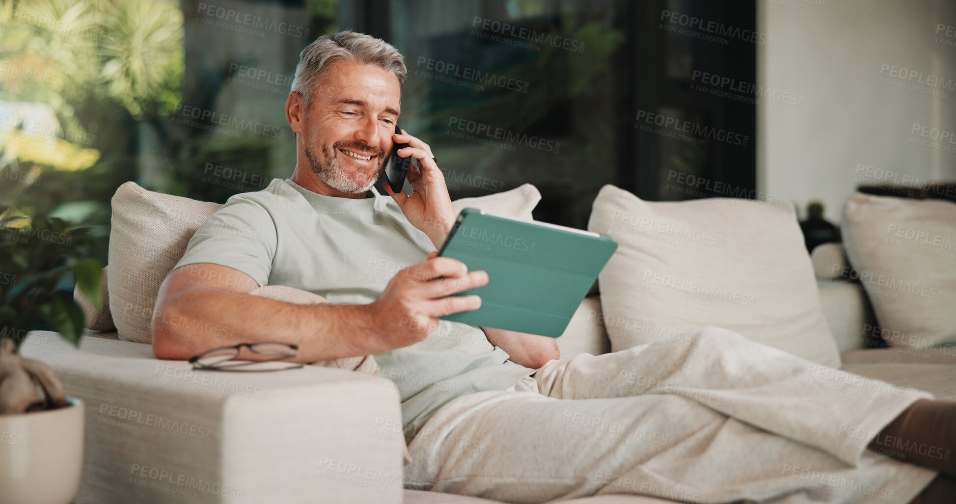 Buy stock photo Phone call, smile and tablet for remote work with man on sofa in home living room as freelancer. App, conversation and research with mature person in apartment for report or review as happy employee