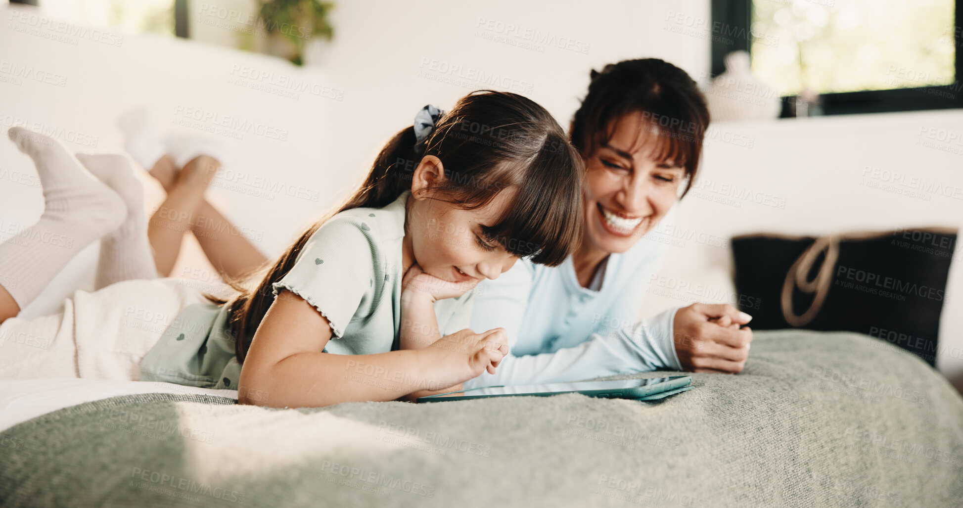 Buy stock photo Mother, daughter and relax on bed with tablet, digital app and play knowledge game for development. Happy family, mom and child learning in home with tech, website and educational gaming for growth.