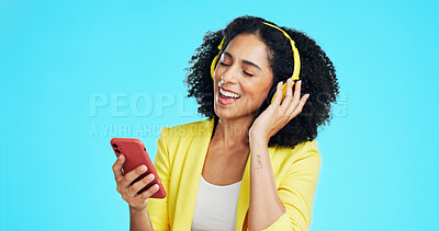 Buy stock photo Headphones, sing and businesswoman with phone in studio for music, album or radio on mobile app. Happy, tech and employee with cellphone for playlist on streaming subscription by blue background.
