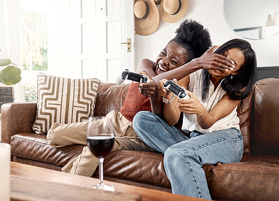 Buy stock photo Gaming, cheating and friends with controller on sofa, playing together and entertainment for bonding. Wine, playful and competitive women with video game in home, online contest and match for smile