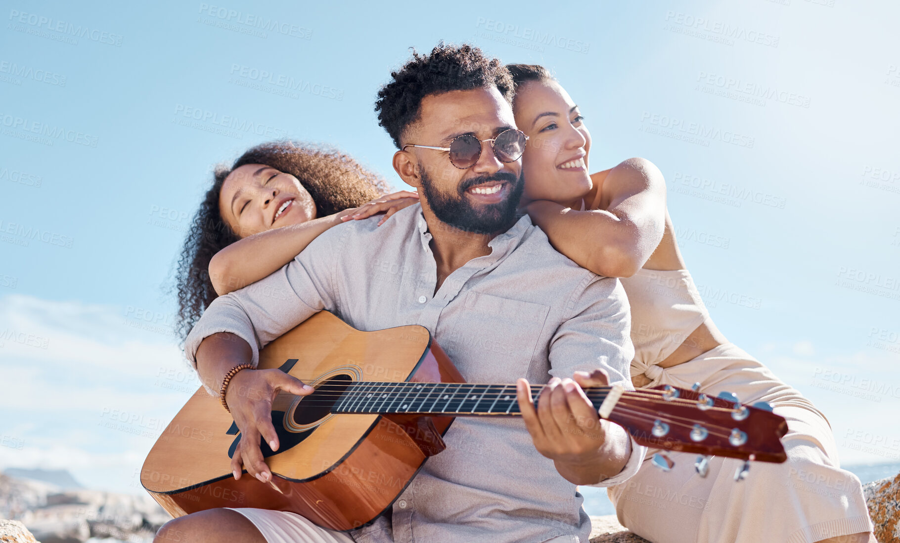 Buy stock photo Smile, summer or friends at beach with acoustic guitar, bonding or fun entertainment on weekend break. Happy, sunshine or people with music instrument, playing song or connection in outdoor getaway.