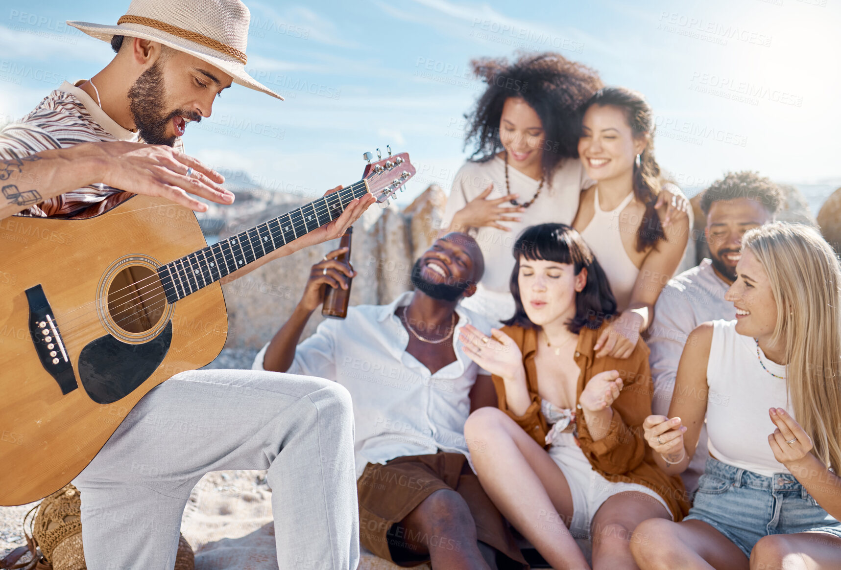Buy stock photo Reunion, acoustic guitar or friends at beach with beer, bonding or fun entertainment on weekend break. Happy, alcohol or people with music instrument, playing song or connection in outdoor getaway.