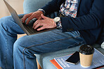 Businessman using laptop computer sitting on sofa in office