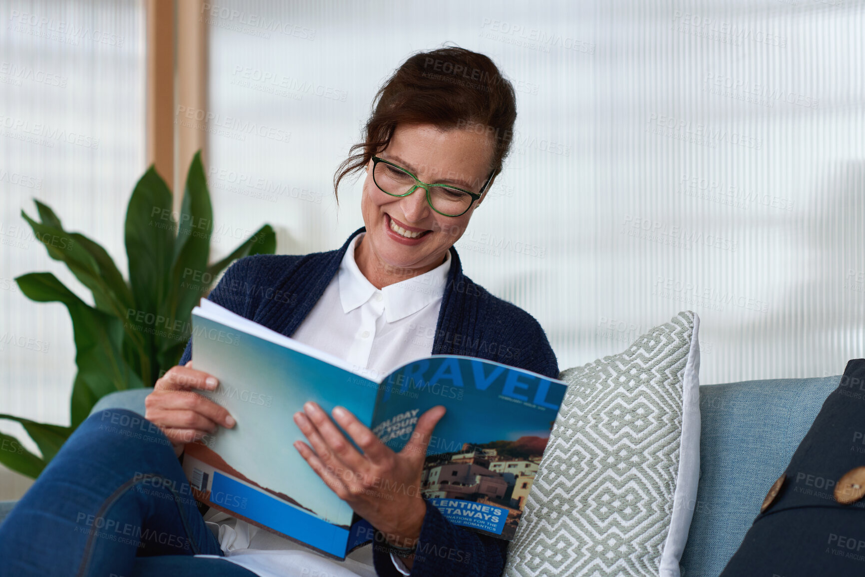 Buy stock photo Happy woman, reading and relax with magazine on sofa with travel review, glasses and article in home. Mature person, publication and story with subscription, smile or break with media in apartment