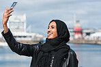 Happy muslim woman taking selfie photo using smartphone camera sharing vacation holding mobile phone wearing hijab