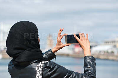 Buy stock photo Travel, photo or Muslim woman in town with phone screen, digital memories or post update on weekend break. Space, back or Arab person with tech, social media picture or memory capture on outdoor trip
