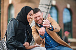 Friends using smartphone watching mobile phone sitting on bench in city