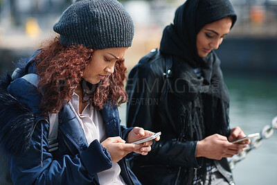 Buy stock photo Woman, phone and texting on promenade by ocean with friends, chat or travel guide on web for vacation. Girl, backpack and typing with mobile app, tourism and social media on holiday at waterfront