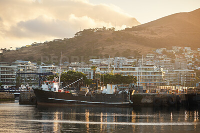 Buy stock photo Outdoor, sea and boat in city with harbor, travel destination and buildings for urban development. Mountain, ocean and fishing vessel in port with coastal town, sunset or scenic for tourist vacation.