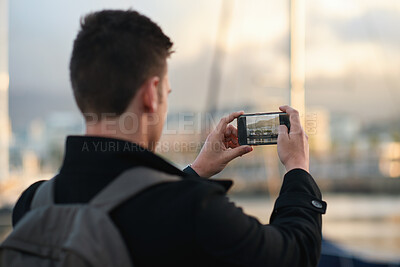 Buy stock photo Travel, photo or man in city with phone screen, online memories or post update on weekend break. Digital, back or person in town with tech, social media picture or memory capture on outdoor trip.