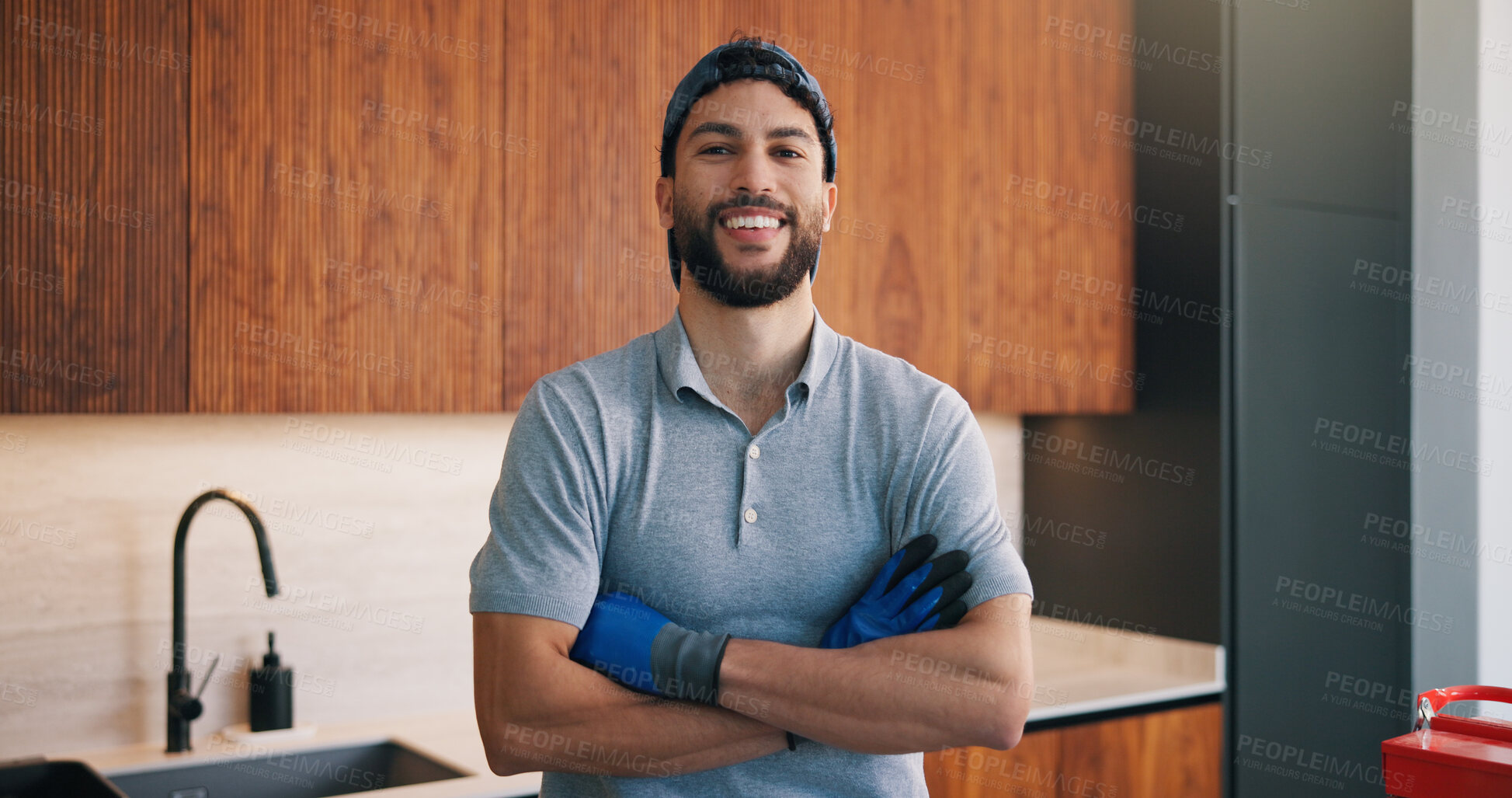 Buy stock photo Portrait, handyman and smile in kitchen with arms crossed, small business or pride for maintenance job. Confident, man and plumber in house with diy repairman, safety and gloves for home improvement.
