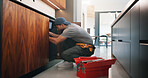 Plumber, man and maintenance in kitchen with tools, repair skills and inspection for quality assurance. Handyman, person and plumbing in home with equipment, fix and check pipeline for restoration.