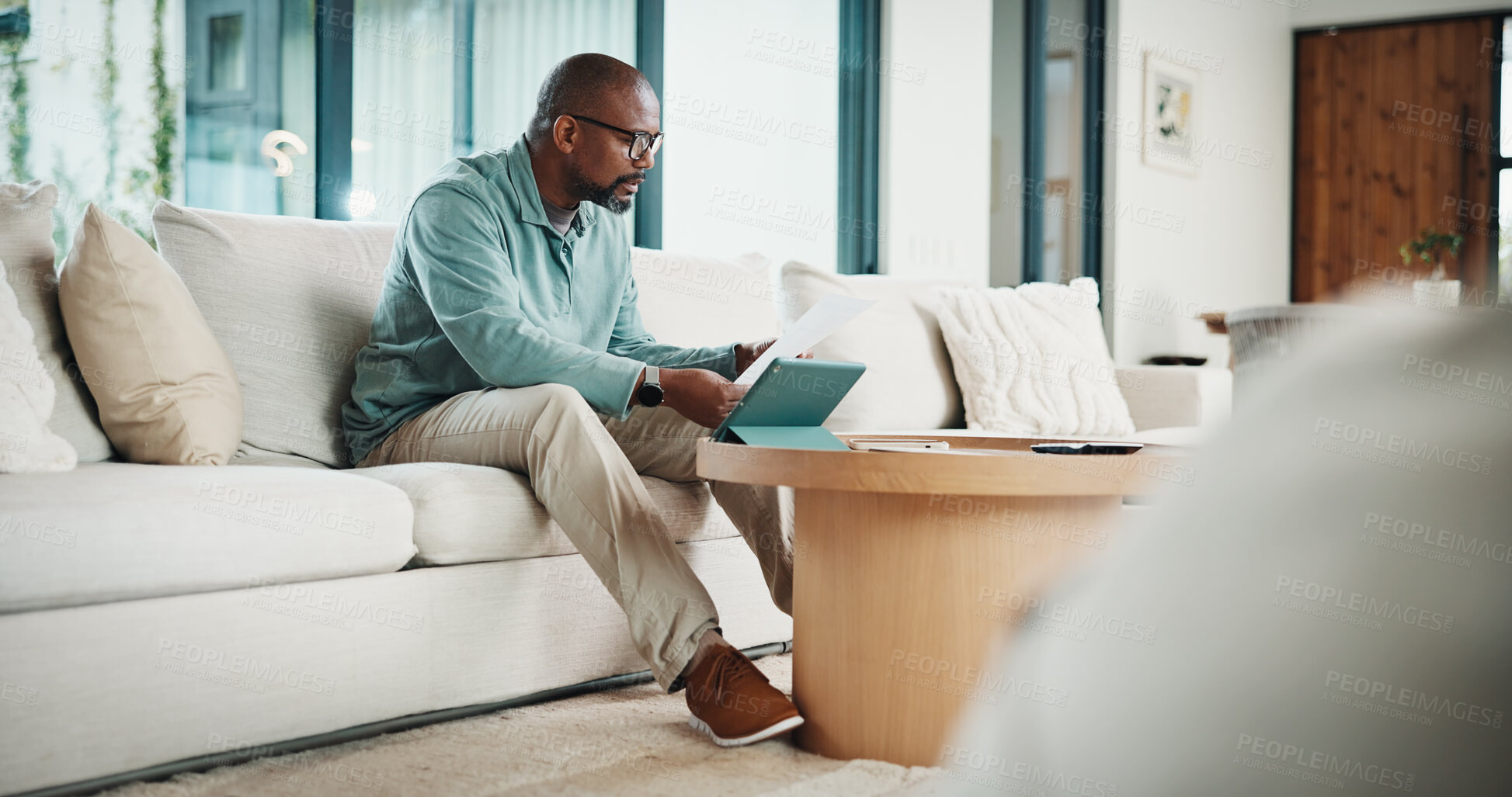 Buy stock photo Paperwork, tablet and black man in home for finance review, budget planning and payment for bills. House, documents and mature person on digital tech for online banking, expenses and financial report