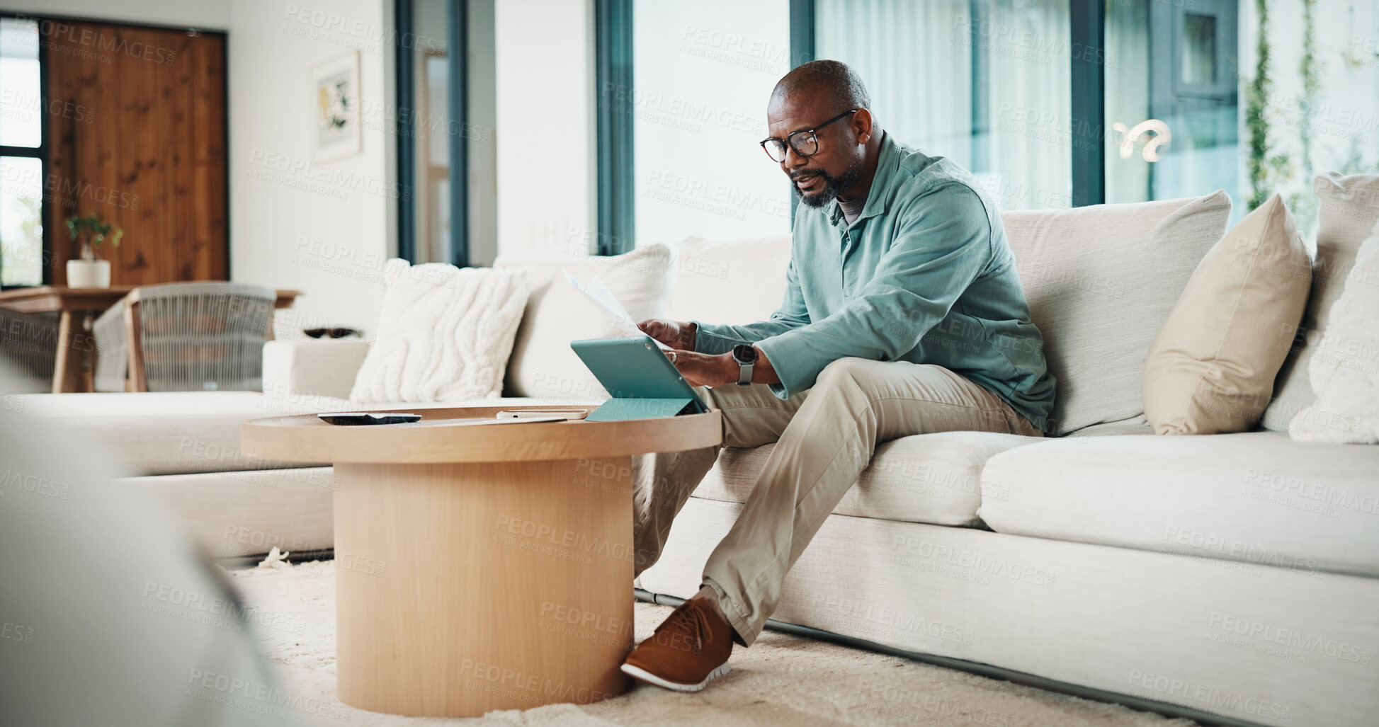 Buy stock photo Documents, tablet and black man on sofa with bills for finance review, budget planning and payment. Home, paperwork and mature person on digital tech for online banking, expenses and financial report