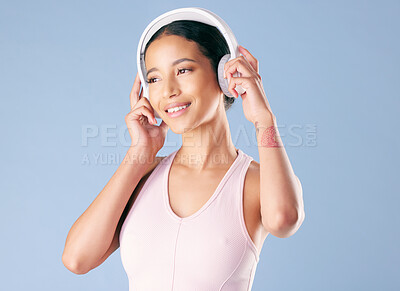 Buy stock photo Happy woman, fitness and thinking with headphones in studio, online and listening to music on break. Blue background, reflection and person with tech for audio, space and streaming song for wellness