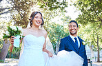 Groom looking at his bride with love as they walk together through nature. Woman lifting her trail as she walks outside in her wedding dress. Happy young couple on their wedding day