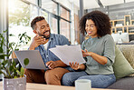 Young happy mixed race couple going through documents and using a laptop at a table together at home. Cheerful hispanic husband and wife smiling while planning and paying bills. Boyfriend and girlfriend working on their budget