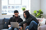 Friends using laptop computer browsing online young woman pointing at screen students working on project sitting on sofa at home