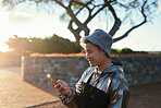 stylish asian man using smartphone texting browsing messages on mobile phone in city at sunset