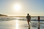 Fit and healthy young adults running out of ocean at sunset