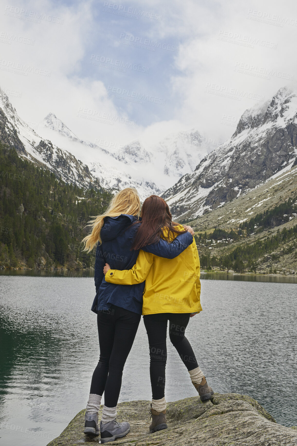 Buy stock photo Hiking, friends and hug with mountain view by lake for adventure, bonding or connection in nature. Trekking, back and women embrace for care, sightseeing or wanderlust together for travel support