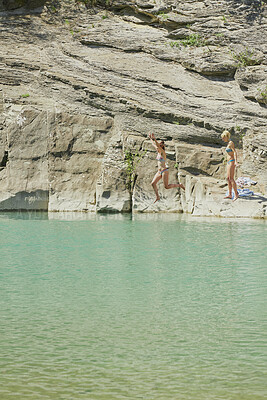 Buy stock photo Jumping, water and girl friends outdoor by rocks for adventure, travel or active on summer holiday. River, freedom and women with leap for swimming together on vacation, getaway or weekend trip.