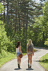 Traveler girl friends walking countryside road on wanderlust adventure vacation
