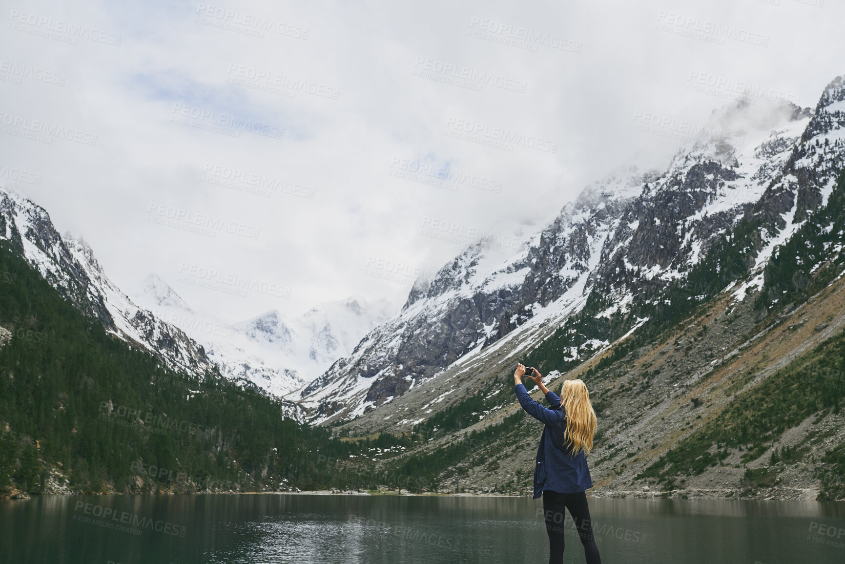 Buy stock photo Back, woman and hiking in nature for photography, social media post and travel blog. Space, female person and phone for profile picture update, trekking scenery and mountain view of wilderness trip