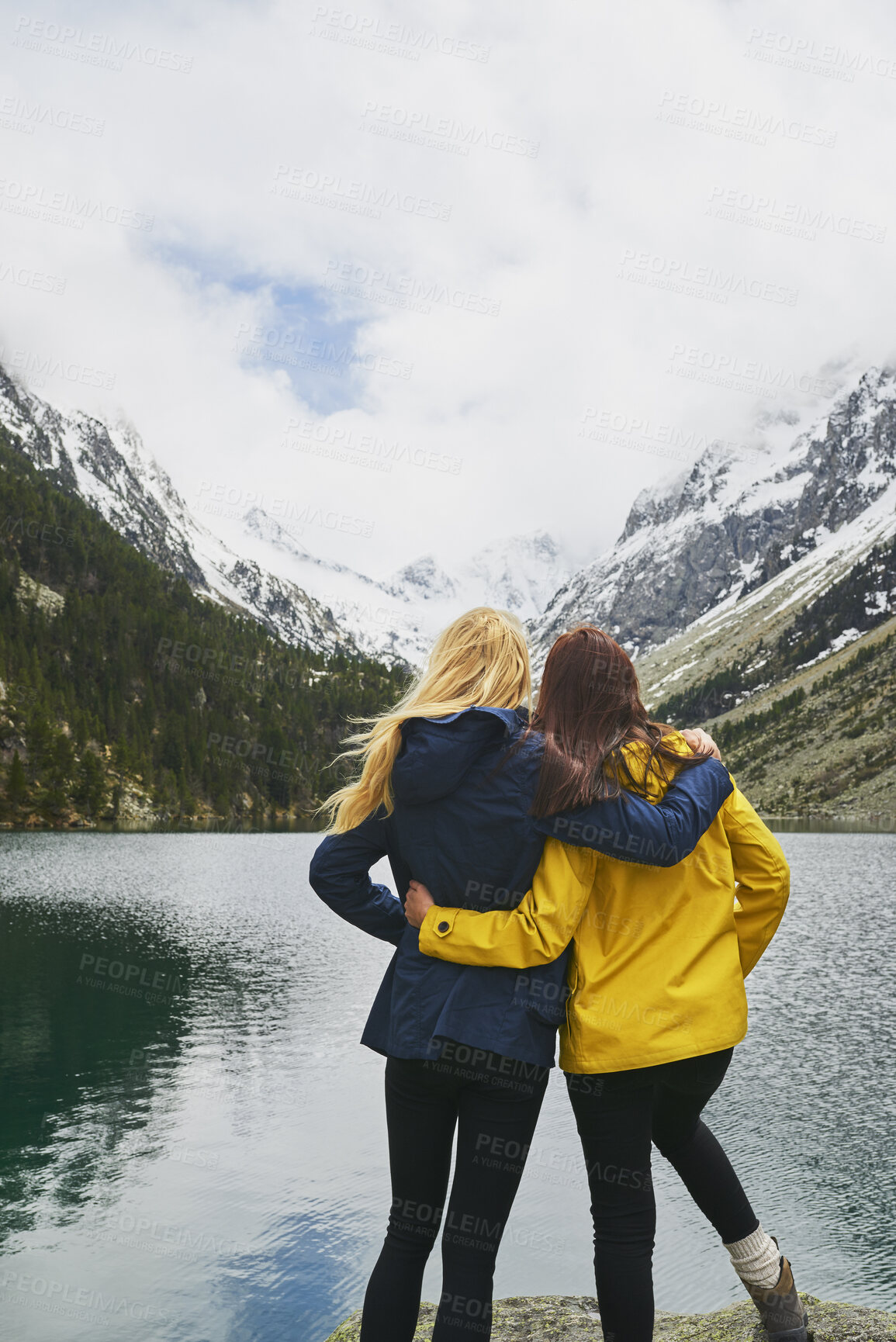 Buy stock photo Trekking, friends and women hug with mountain view by lake for adventure, bonding or connection in nature. Hiking, back and people embrace for care, sightseeing or wanderlust together by water