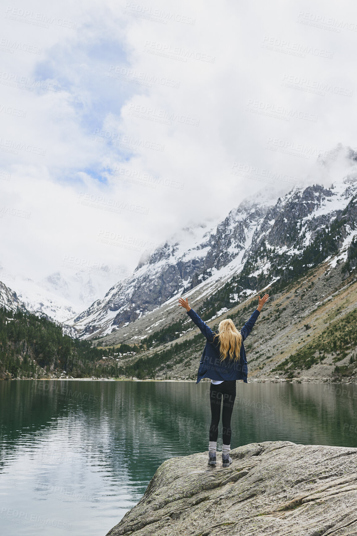 Buy stock photo Lake, mountain and hiker with arms up for success, celebration or hiking achievement. Travel, nature and person on cliff with back for winter journey, adventure or exploration for snow and water