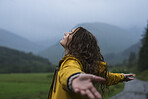 Happy young woman standing in rain with her arms outstretched rejoicing, celebrating and enjoying life