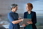 Business people using digital tablet computer in office mature team leader woman working with colleague discussing information on touchscreen device