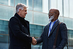 Mature businessmen shaking hands in city with businessman greeting african american client with handshake
