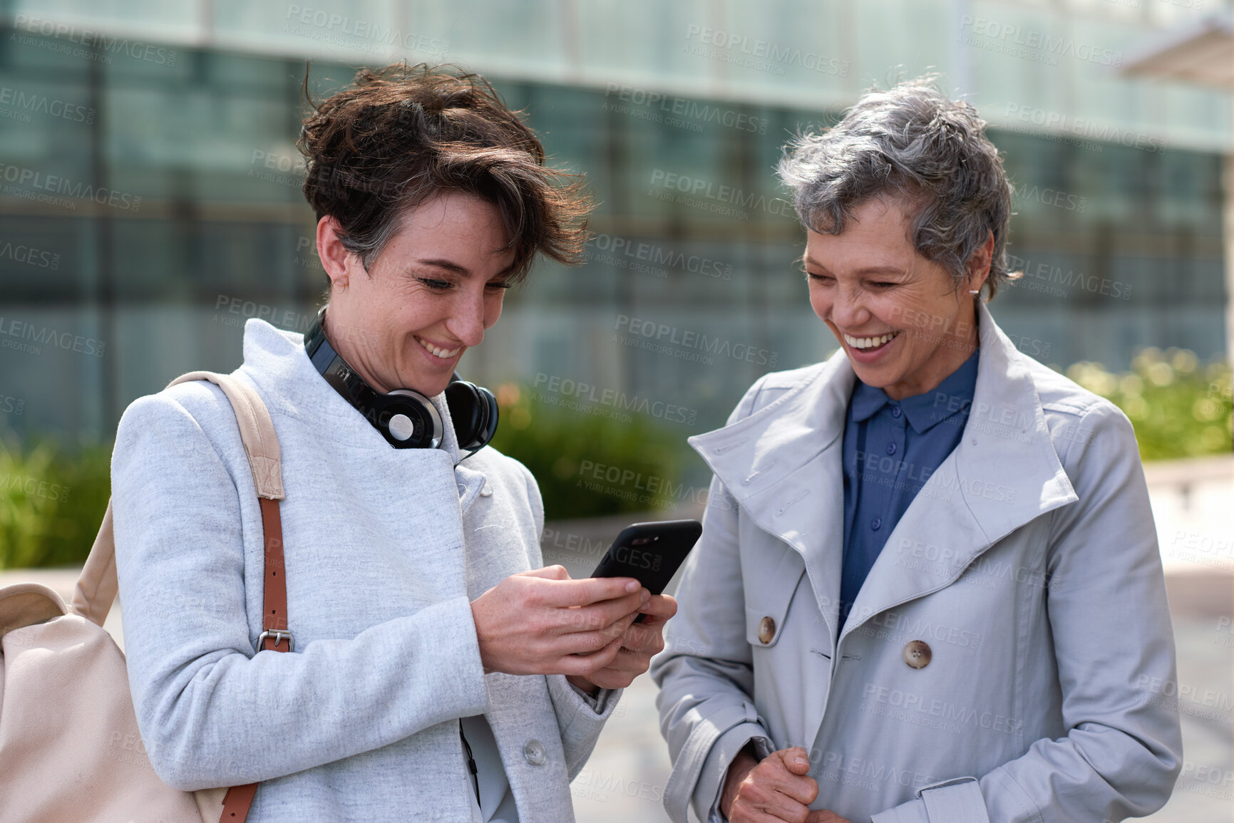 Buy stock photo Phone, smile and business women in city for social media, commute and morning communication online. Travel, conversation and friends with tech for laugh, humor or funny joke and networking or bonding
