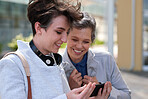 Two business women friends using smartphone in city smiling looking at mobile phone