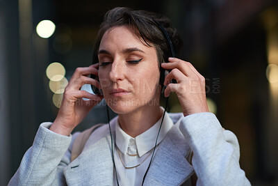 Buy stock photo Night, city and business woman with headphones, streaming service or listening to travel playlist. Audio, employee and person outdoor for podcast subscription with music, radio and bokeh on commute
