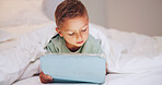Learning, child and relax in bed with tablet, puzzle game or online platform for language development. Boy kid, tech and network in home for multimedia, educational app or memory challenge on website