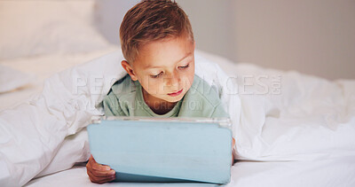 Buy stock photo Learning, child and relax in bed with tablet, puzzle game or online platform for language development. Boy kid, tech and network in home for multimedia, educational app or memory challenge on website