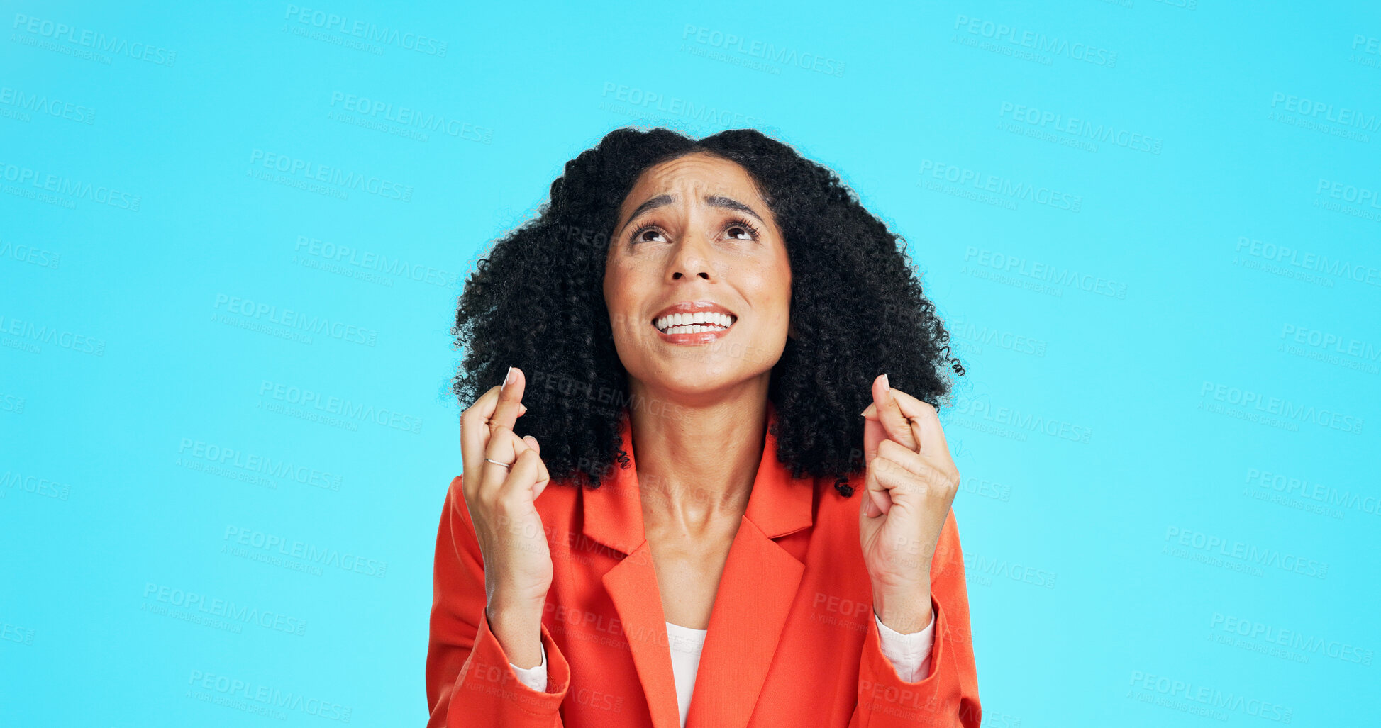 Buy stock photo Praying, woman and fingers crossed in studio with stress for promotion, deal or feedback. Wish, person or worker with luck emoji for anxiety, nervous or waiting for announcement on blue background