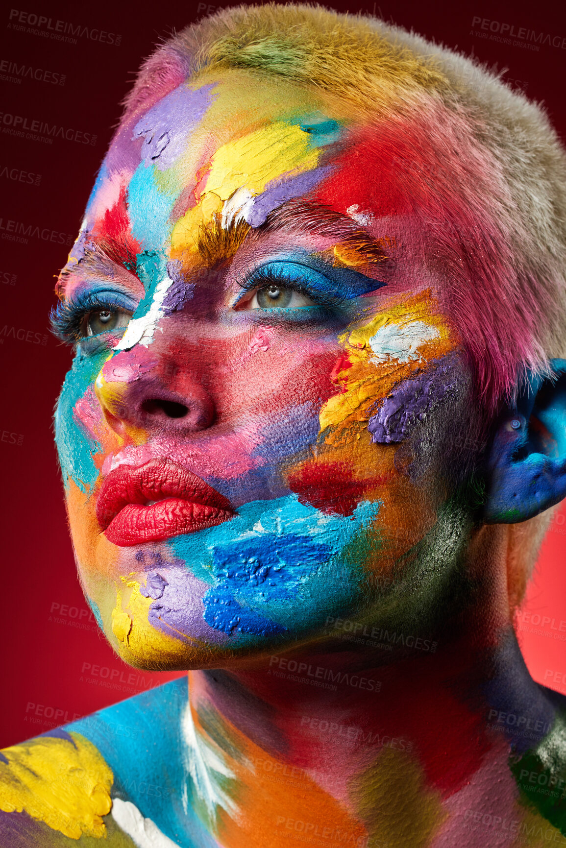 Buy stock photo Woman, face paint and rainbow with beauty in studio for texture, art deco or thinking on red background. Girl, creative makeup and cosmetics with skin, transformation and multicolor with perspective