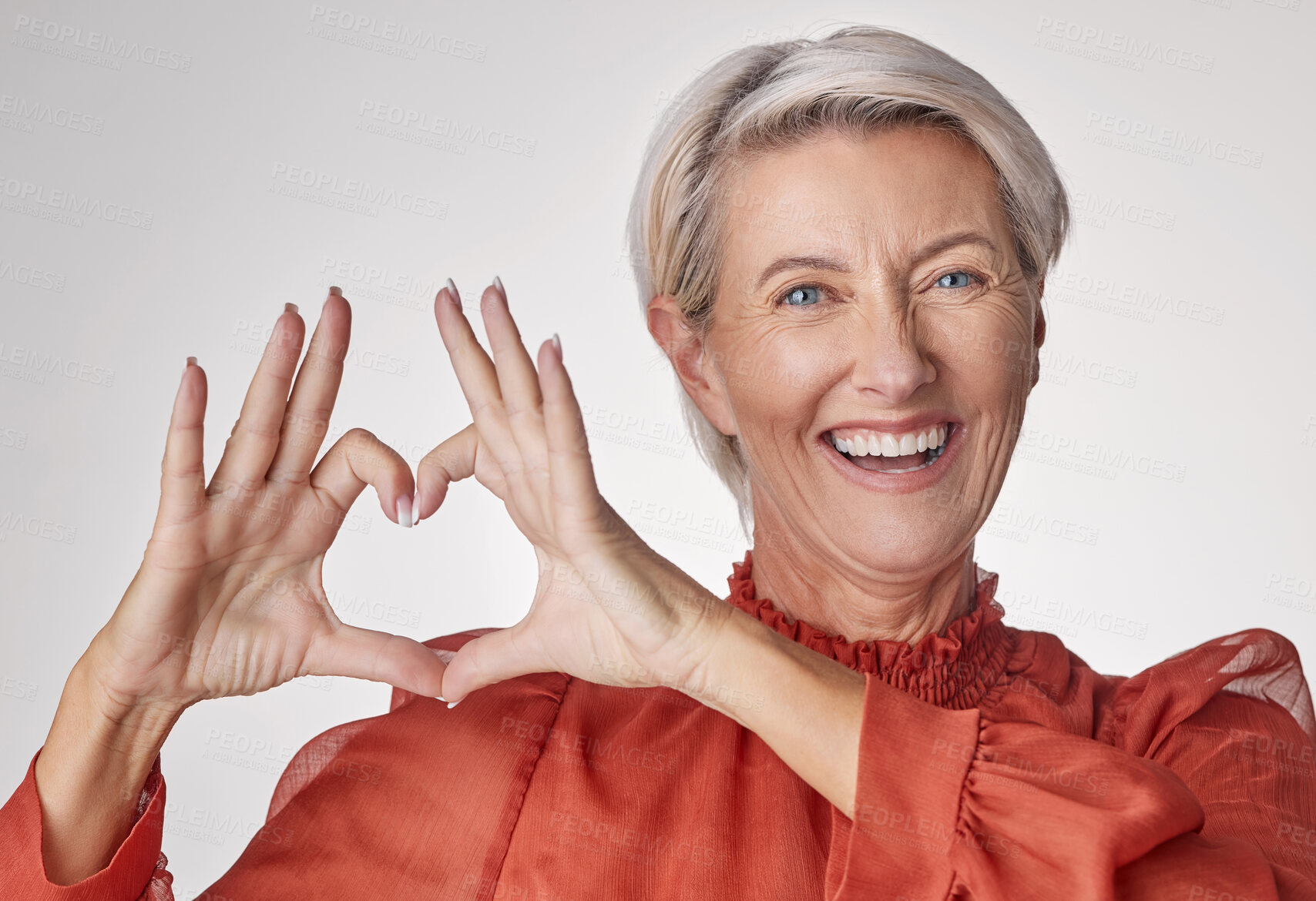 Buy stock photo Mature, portrait and happy woman with heart hands in studio for love on a white background. Female person, romance or valentines day with smile, like emoji or shape for romantic gesture or care