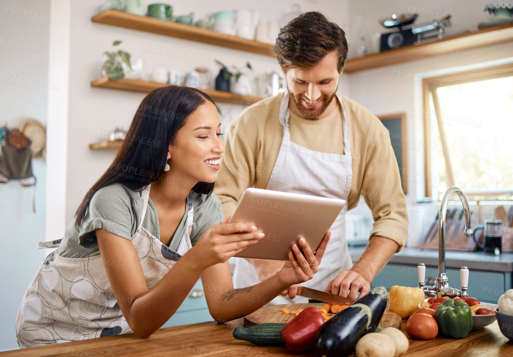 Buy stock photo Tablet, cooking or interracial couple in home with smile, vegetable recipe or nutrition blog. Tech, man and woman at kitchen for meal prep, healthy food guide or cut carrots for organic vegan diet