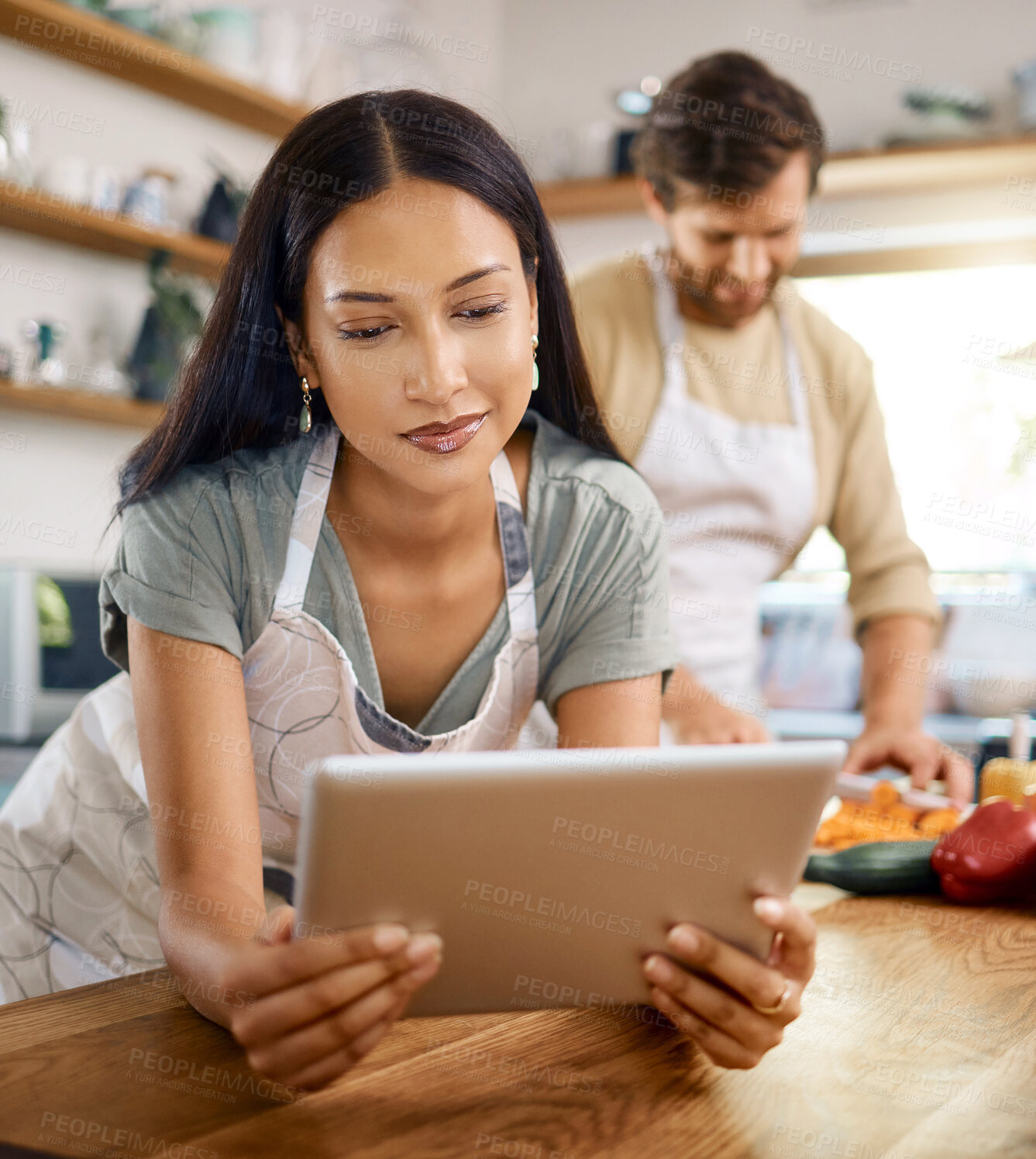 Buy stock photo Tablet, cooking or woman in kitchen with interracial couple, online recipe or nutrition blog. Reading, tech and people at home to meal prep, food guide website or research ingredients for vegan diet