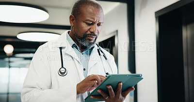 Buy stock photo Doctor, man and reading in hospital with tablet, medical research or problem solving for telehealth. Mature black person, healthcare worker and scroll in clinic with tech, patient records and report.